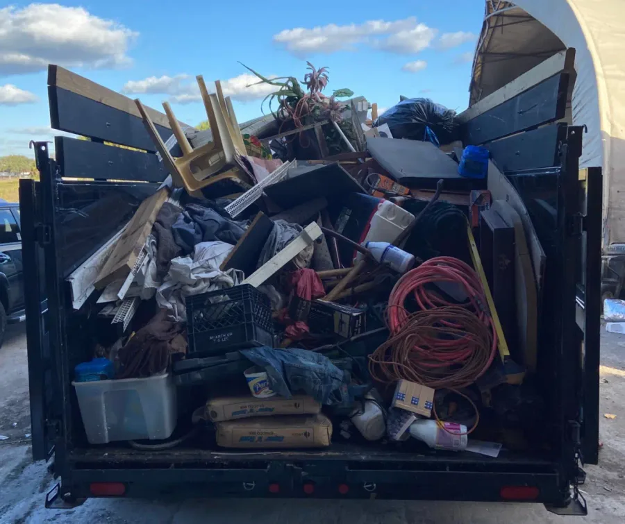 Homeowner loading household junk into a MAXCO dumpster trailer