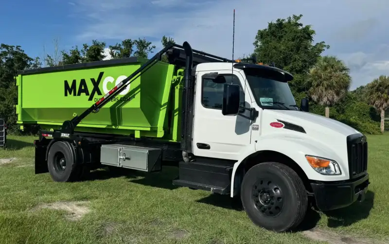 MAXCO Dumpsters roll-off truck loaded with a green dumpster, ready for delivery in New Port Richey